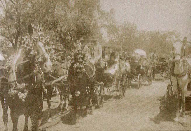 (Desfile de coches con caballos enjaretados)