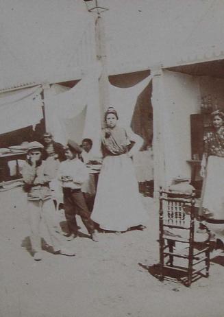 (Retrato de un grupo de gitanos frente a unas casetas)