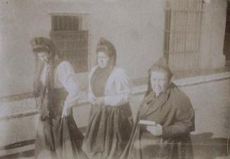 (Tres mujeres con mantilla paseando por una calle)