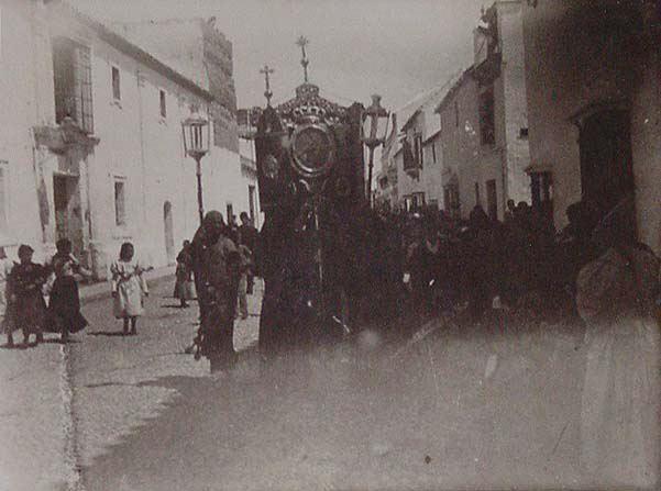 (Procesión religiosa en una calle portando un gran estandarte)