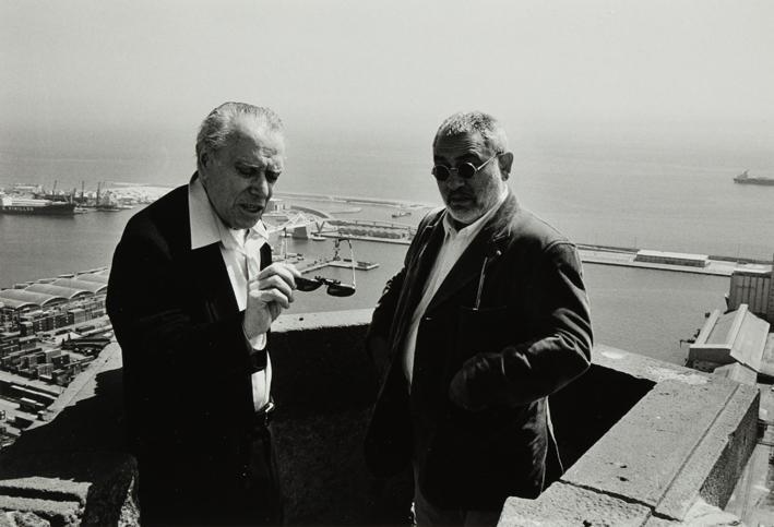 Dos hombres en un mirador con vistas al mar (puerto)