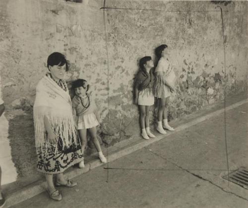 Chica y niñas apoyadas en una pared