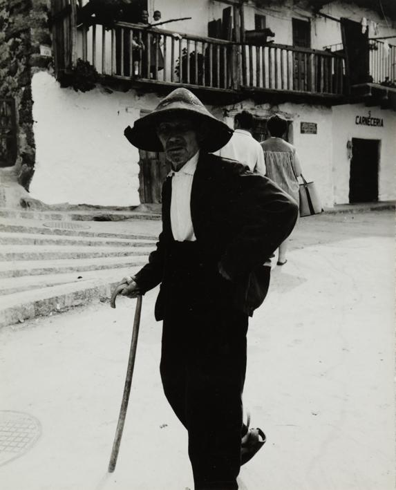 Hombre con sombrero y bastón en la calle de un pueblo