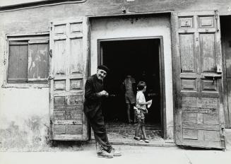 Hombre mayor y niño en la puerta de una casa