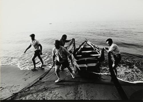 Pescadores y barca en la orilla del mar