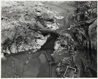 Vista del curso de un río en valle rocoso, junto a estructuras de la presa de El Vado