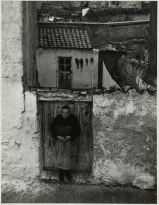 Mujer mayor en la puerta de una casa de pueblo