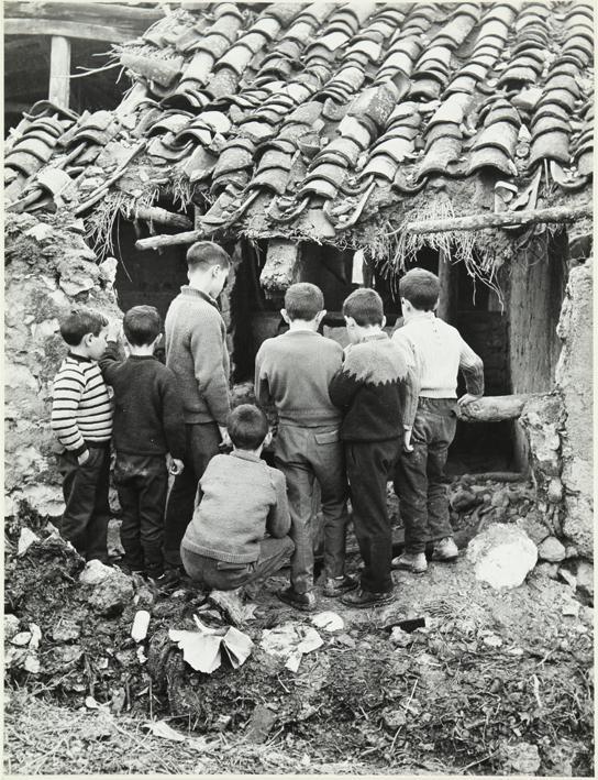 Grupo de niños observan casa rural en ruinas