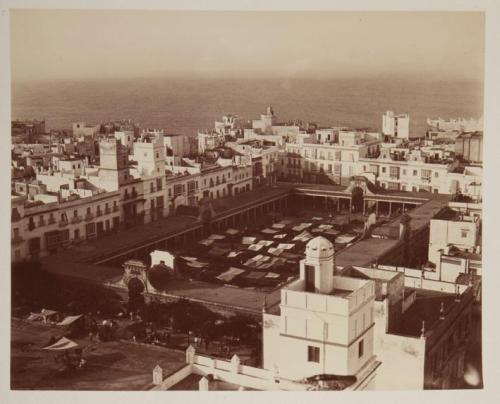 Vista de ciudad con mar: plaza rodeada de casas blancas