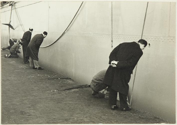 (Hombres mirando el casco de un barco)