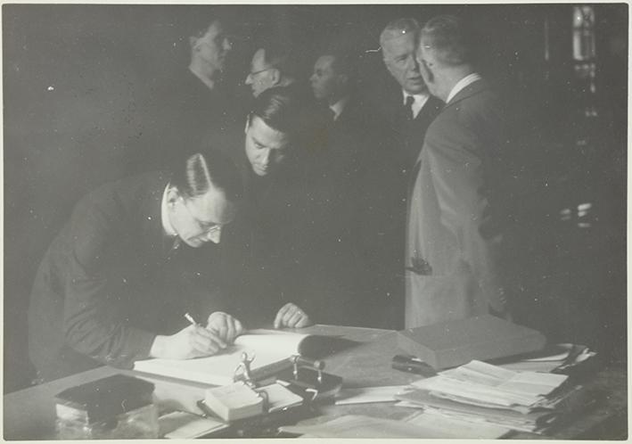 (Hombre firmando en el Llibre d´Or del Comissariat de Propaganda ante la mirada de Jaume Miravitlles)