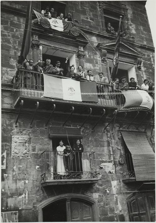 (Público asomado a las ventanas durante un desfile militar))