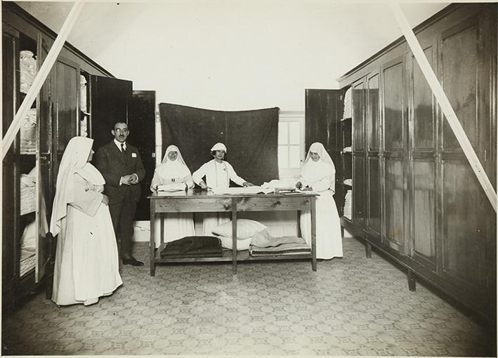 (Personal y monjas de un sanatorio guardando ropa blanca)